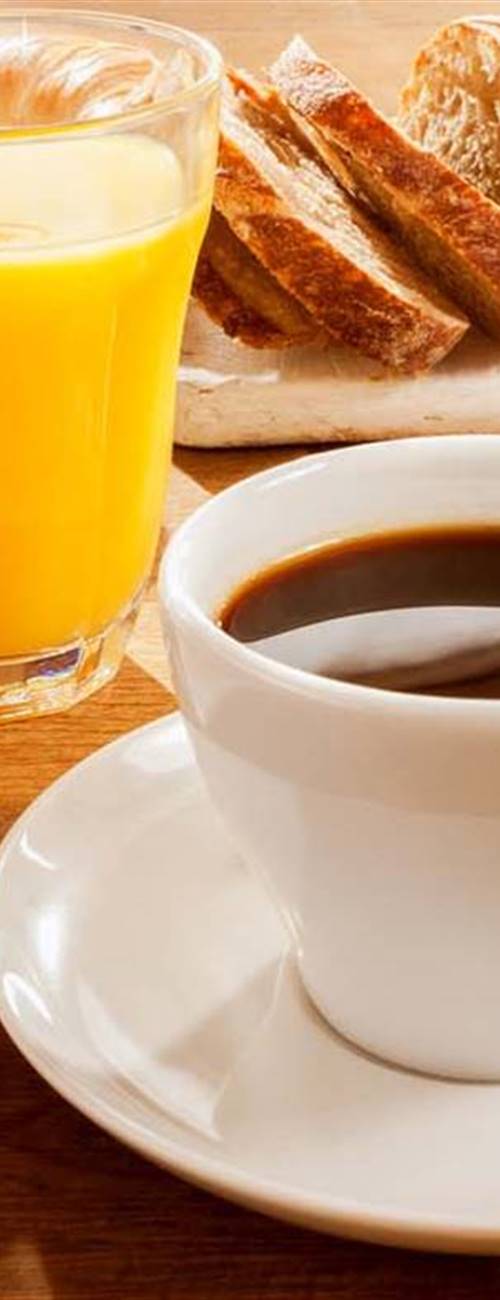 Breakfast table with coffee, pastries, muesli, eggs, fruit and juice in detail